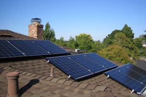 solar panels on  roof of house with trees and blue sky in the background