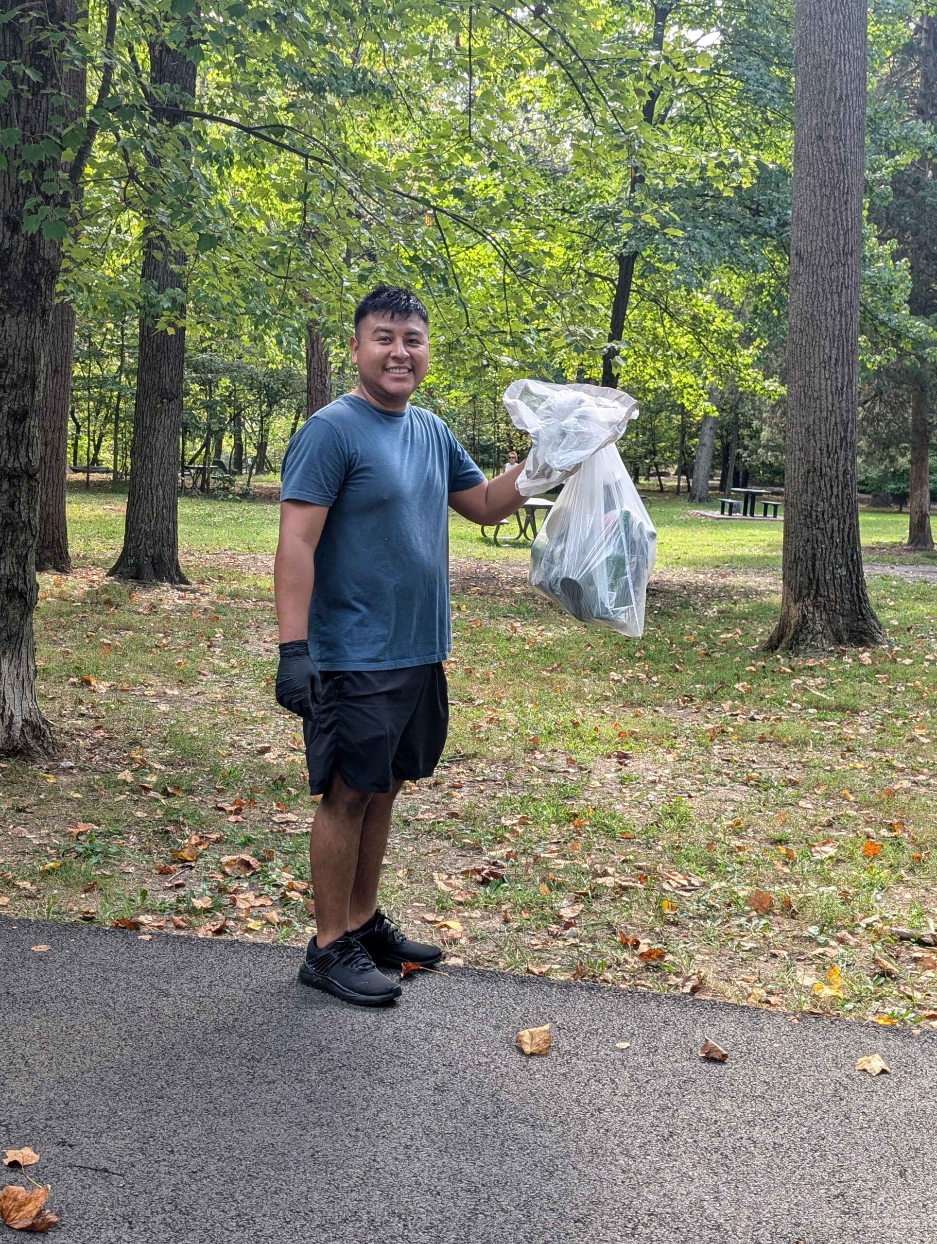 a volunteer holds up a garbage bag full of trash he collected at Barcroft park