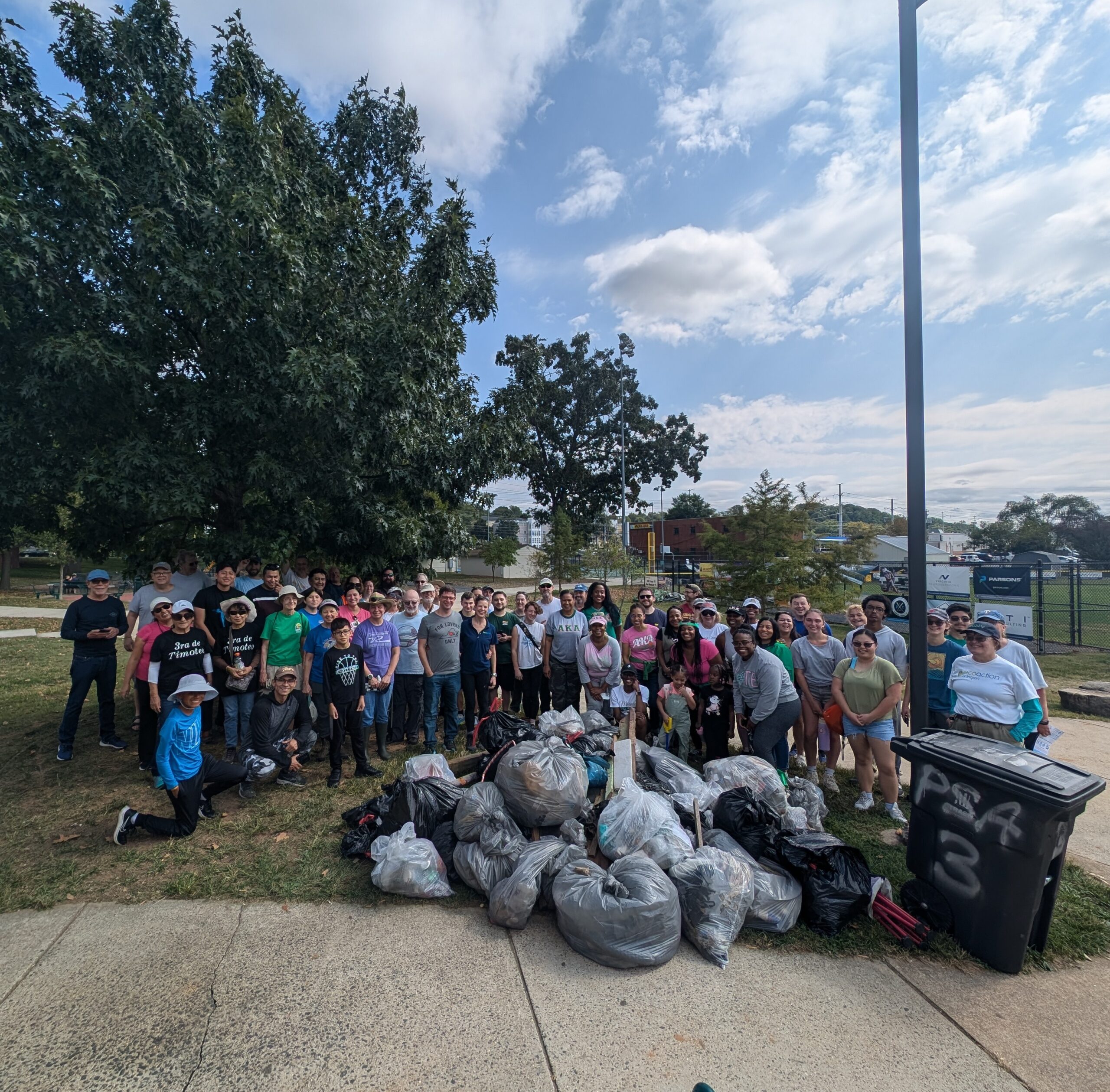 volunteers pose in front of bags of trash and debris collected at Barcroft park