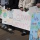 photo close up of hands holding climate action signs at the Climate Resolution Rally on 2/22/2025 in Arlington. Photo courtesy of Molly Bolan.