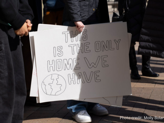 Photo close up of sign at the rally on 2/22/2025 with attendees legs seen around the sign. Sign reads: Tis sis the only Home we have in large black block letters.