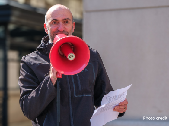 close up of Mike Lowe, EcoAction Arlington Board Chair, speaking into a red megaphone. Photo credit: Bryan Scafford.